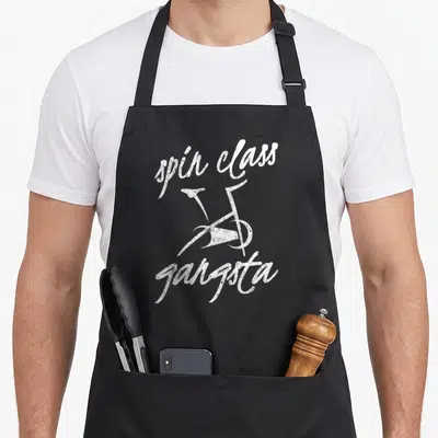 Gangsta bike apron - White bicycle between spin class and gangsta script text — shown on a black cotton canvas apron against a white background