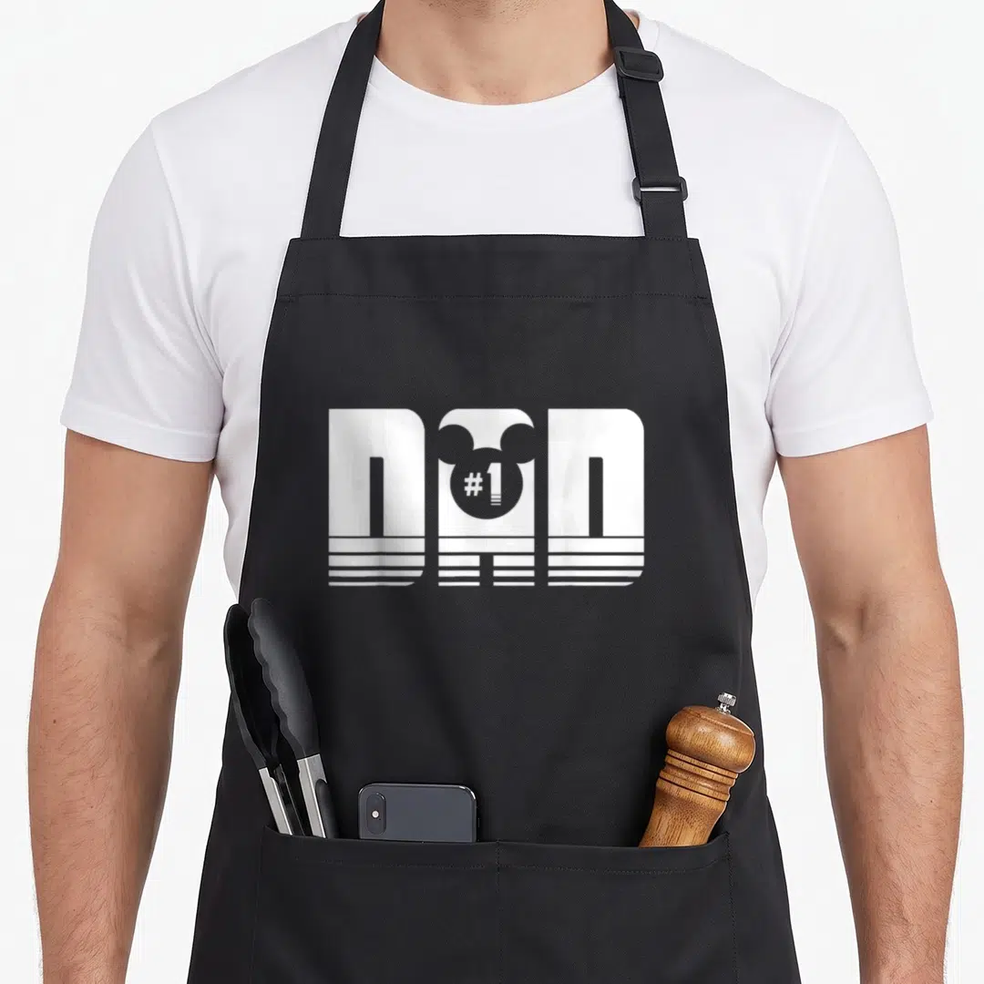 Icon mouse dad apron - White DAD text with Mickey head silhouette containing #1 on black apron — shown on a black cotton canvas apron against a white background