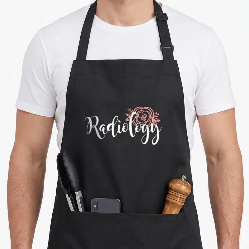 Rad tech x ray apron - White script word Radiology with a peach line-art flower overlapping the text — shown on a black cotton canvas apron against a white background