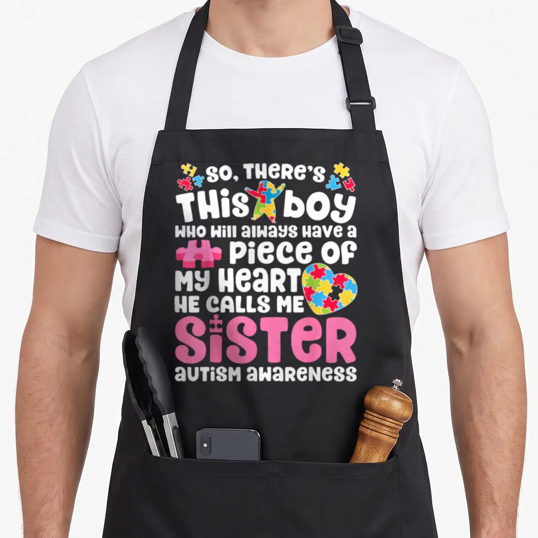 Call nun apron - So there's this boy autism awareness text with puzzle heart and figure in pink white blue yellow red — shown on a black cotton canvas apron against a white background