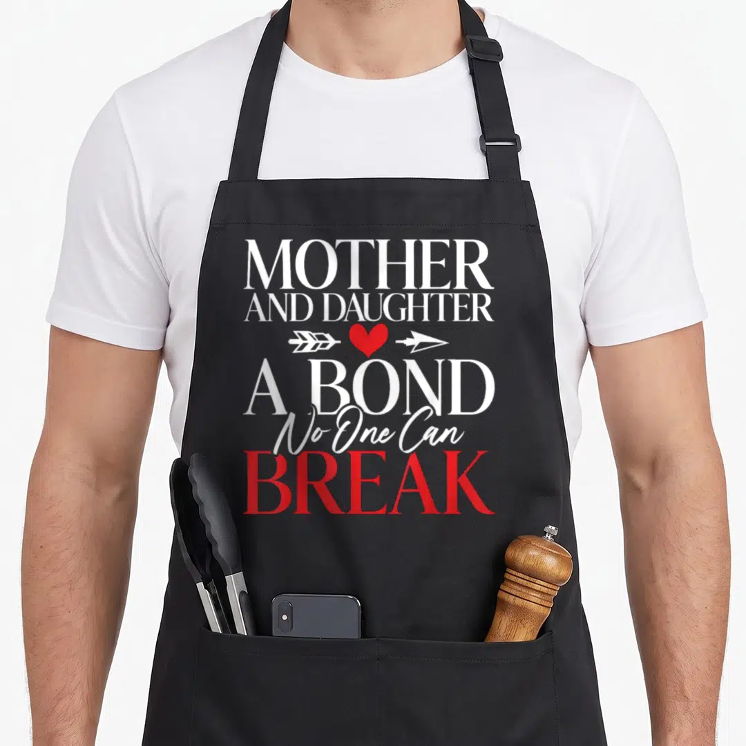 Bond mother daughter apron - Stacked text MOTHER AND DAUGHTER A BOND No One Can BREAK with red heart and white arrow — shown on a black cotton canvas apron against a white background