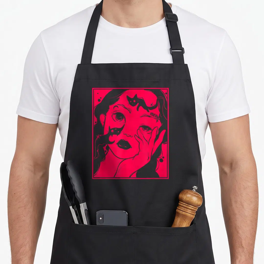 Grunge kawaii cooking apron - Woman face in pink square with two grey cats and meow tattoo on forehead — shown on a black cotton canvas apron against a white background