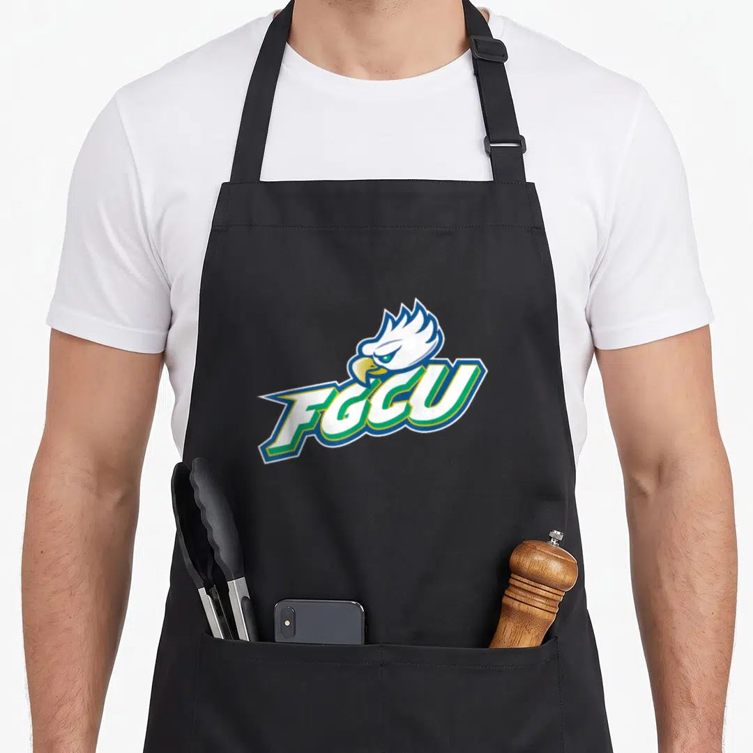 Florida eagles apron - Cartoon eagle head behind slanted FGCU text in white blue green and yellow — shown on a black cotton canvas apron against a white background