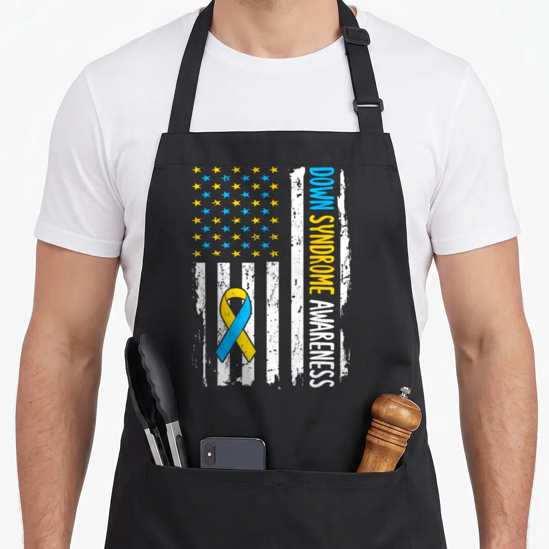Syndrome american flag apron - Distressed US flag with blue yellow stars and centered awareness ribbon reading DOWN — shown on a black cotton canvas apron against a white background