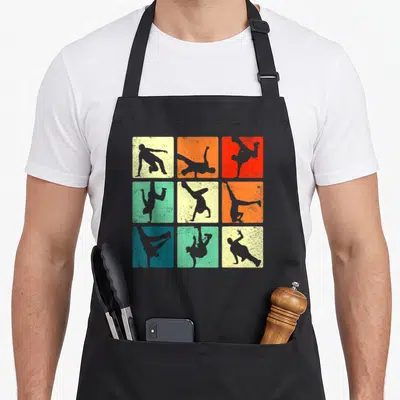 Break hip apron - Nine square panels showing grey break dancer silhouettes in retro vintage poses on textured — shown on a black cotton canvas apron against a white background