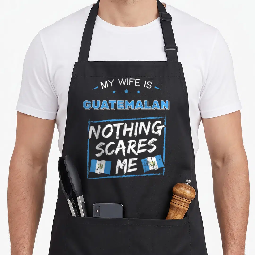 Guatemalan wife apron - My Wife Is Guatemalan Nothing Scares Me text with two flags in distressed blue and white — shown on a black cotton canvas apron against a white background