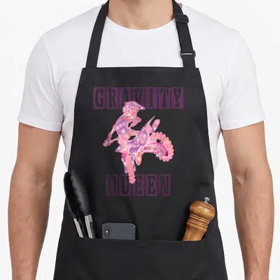 Gravity bike apron - Purple and pink cartoon motocross rider centered between stenciled GRAVITY and QUEEN text — shown on a black cotton canvas apron against a white background