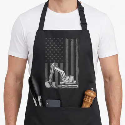 Excavator heavy canvas aprons - Grey excavator illustration in front of a distressed American flag pattern — shown on a black cotton canvas apron against a white background