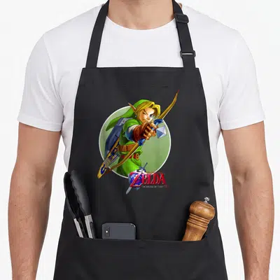 Ocarina novelty apron - Link aiming bow in front of green circle with game logo overlapping waist — shown on a black cotton canvas apron against a white background