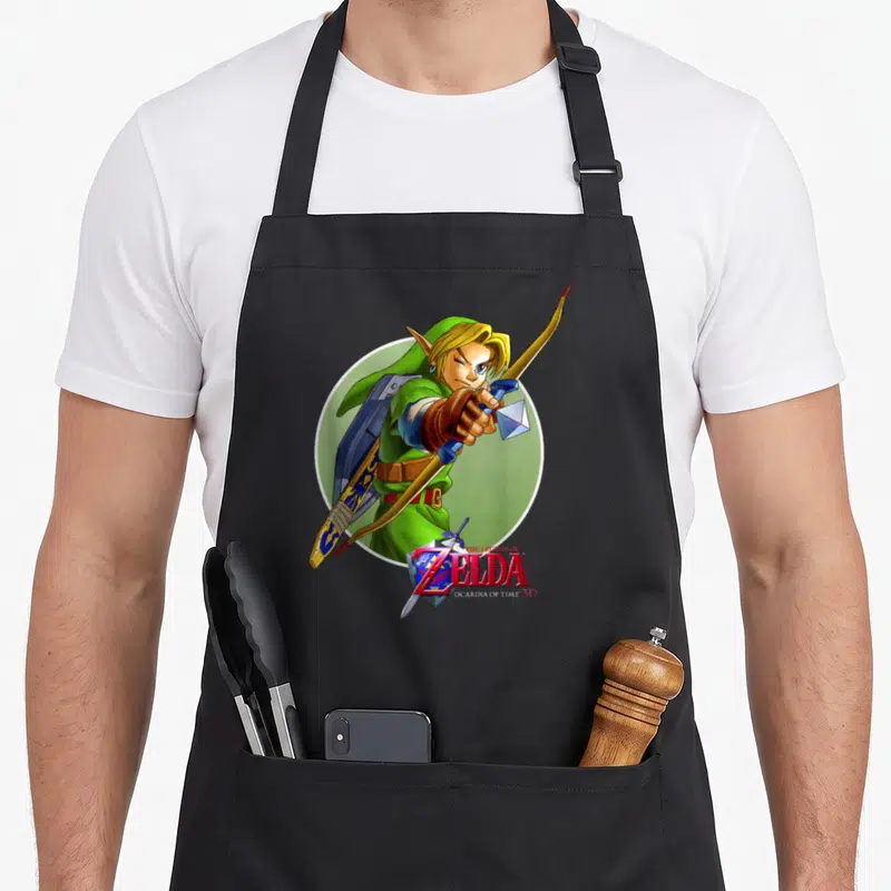 Ocarina novelty apron - Link aiming bow in front of green circle with game logo overlapping waist — shown on a black cotton canvas apron against a white background