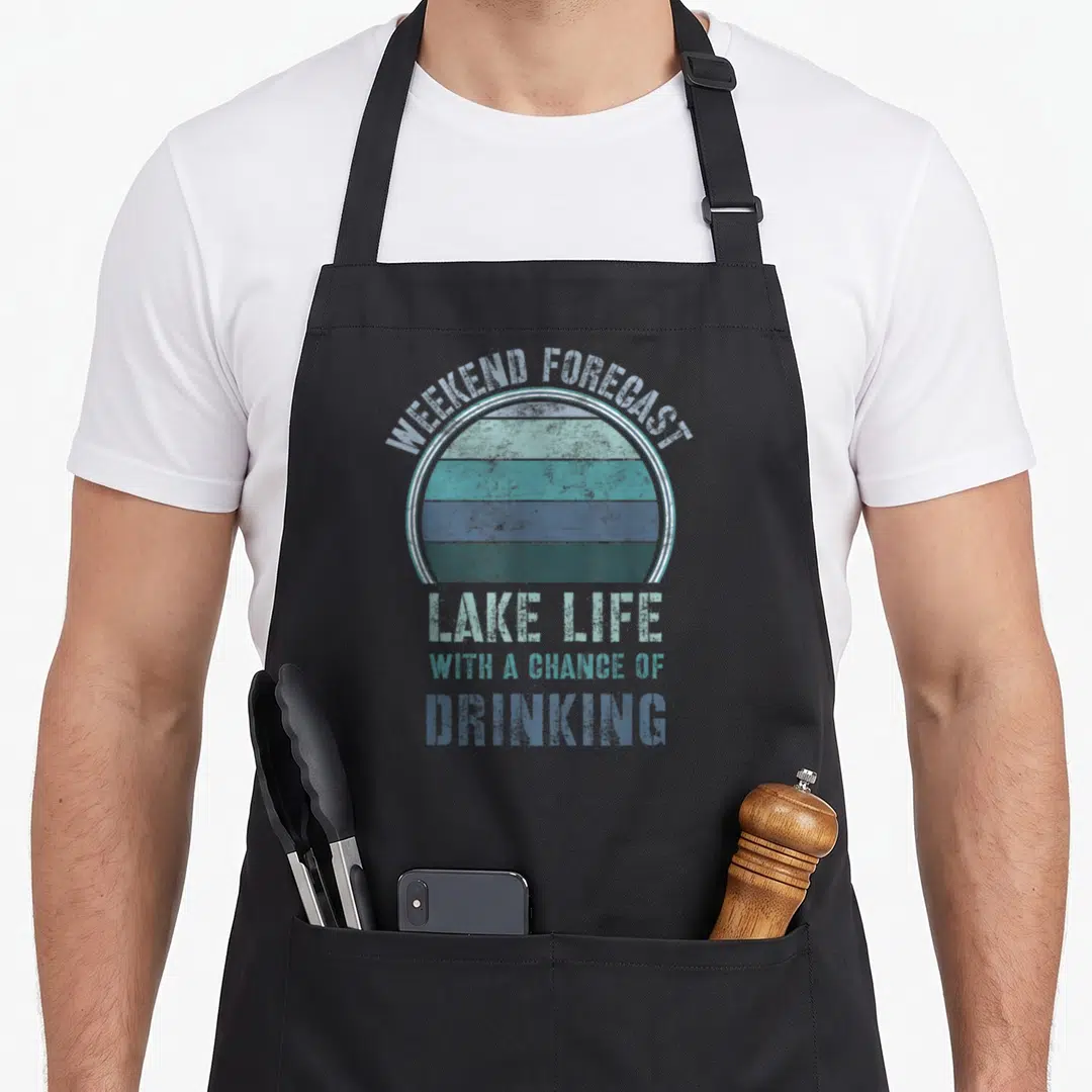Lake summer life apron - Distressed blue sunset graphic with arched text reading Weekend Forecast Lake Life — shown on a black cotton canvas apron against a white background