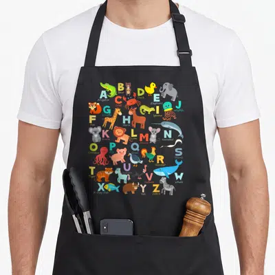 Alphabet animal apron - Cartoon letters A to Z paired with animals including Alligator, Bear, Crab, and Zebra in bright — shown on a black cotton canvas apron against a white background