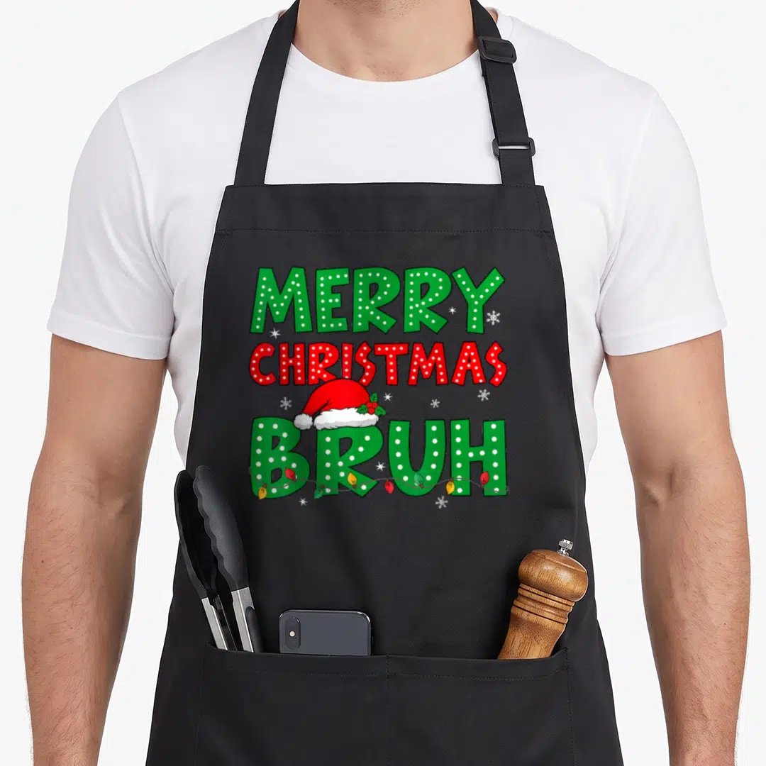 Bruh christmas apron - Merry Christmas Bruh text with Santa hat, string lights, and snowflakes in green and red — shown on a black cotton canvas apron against a white background