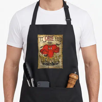 Depth crazy bunny man apron - Red monster on weathered paper with IT CAME FROM THE METROPOLIS text and grey bats — shown on a black cotton canvas apron against a white background