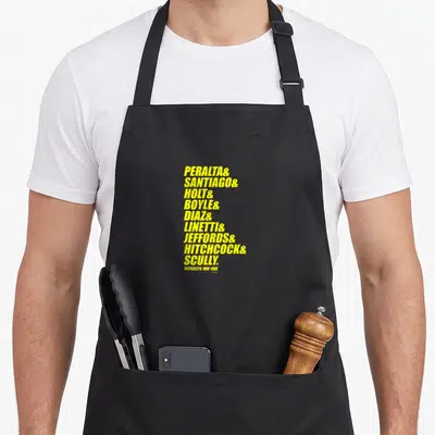 Ampersand brooklyn apron - Yellow stacked surnames Peralta Santiago Holt Boyle Diaz Linetti Jeffords Hitchcock Scully — shown on a black cotton canvas apron against a white background