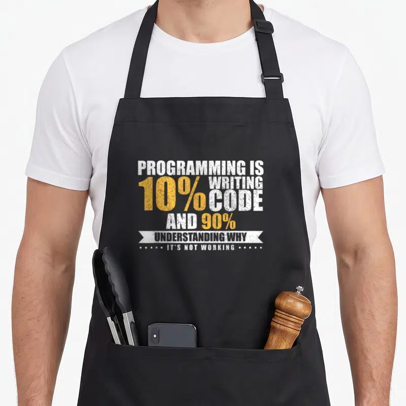 Programmer programming apron - Stacked white and yellow text reading 10% code 90% understanding why its not working — shown on a black cotton canvas apron against a white background