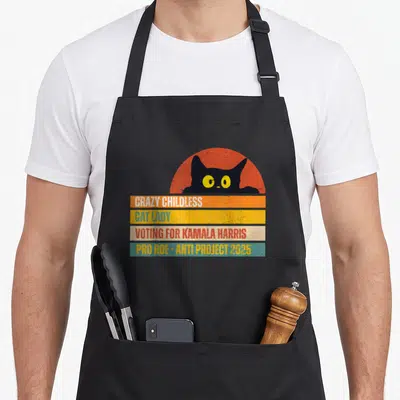 Childless crazy cat lady apron - Black cat head in orange sun above bars reading Crazy Childless Cat Lady Voting — shown on a black cotton canvas apron against a white background