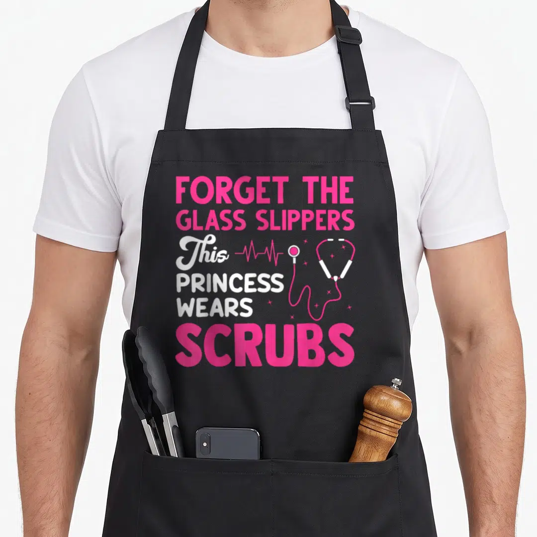 Week medical nurse apron - Pink and white text reading forget glass slippers princess wears scrubs with stethoscope — shown on a black cotton canvas apron against a white background