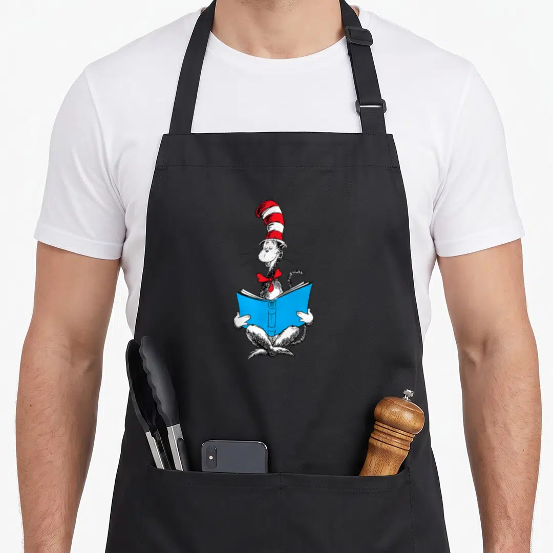 Reading cat apron - Line art of a cat in a striped hat holding an open blue book — shown on a black cotton canvas apron against a white background
