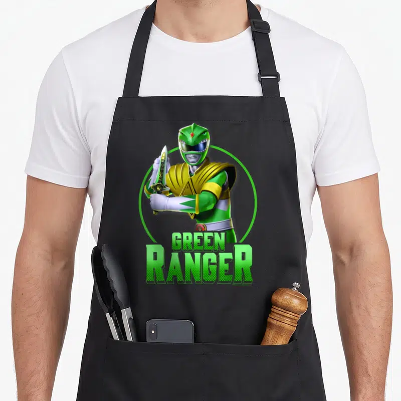 Karate rangers apron - Green Ranger holding sword inside green circle with stacked text below — shown on a black cotton canvas apron against a white background