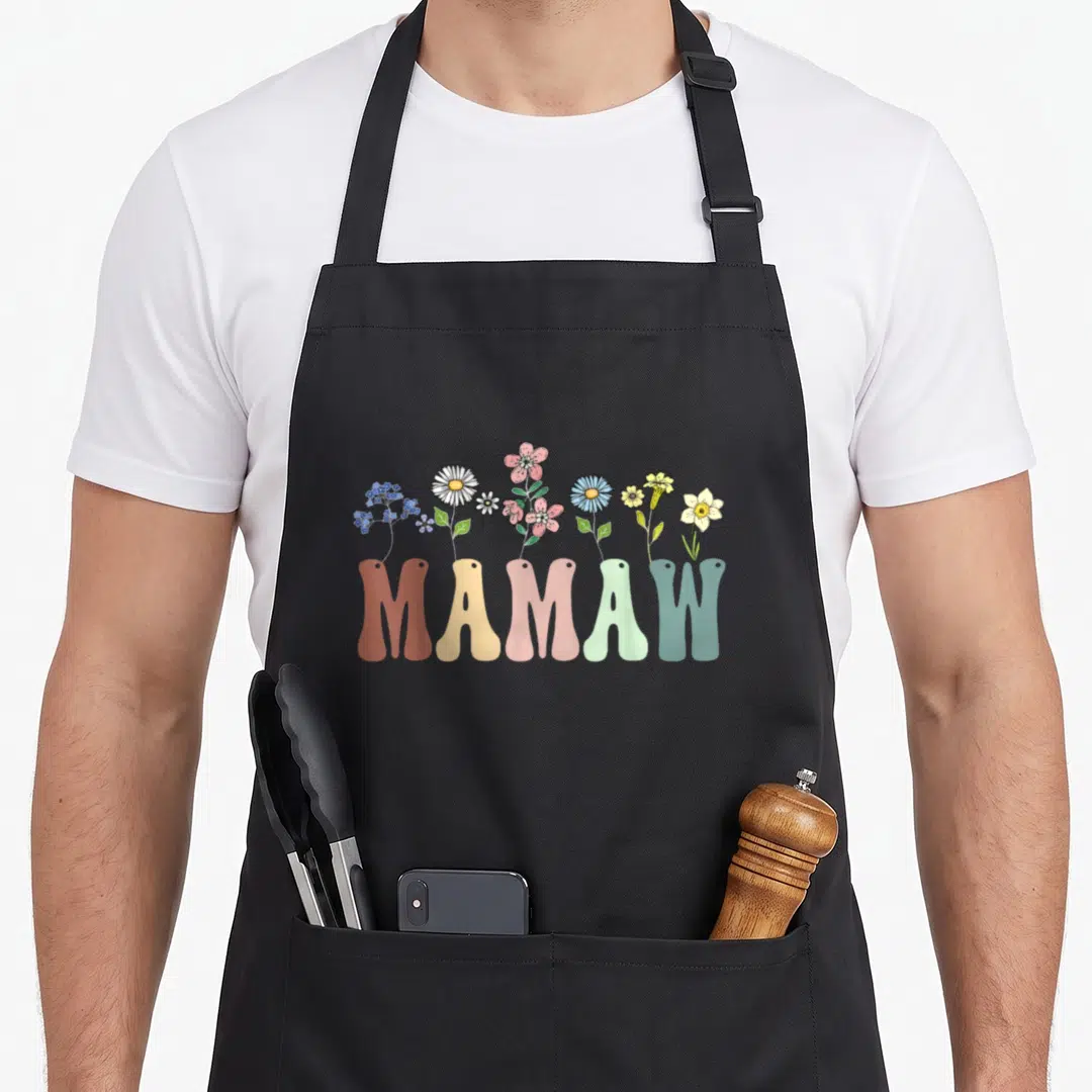 Mamaw floral apron - Colorful wildflowers growing out of the word MAMAW in cartoon style — shown on a black cotton canvas apron against a white background