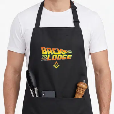 Lodge freemason apron - BACK TO THE LODGE text in yellow orange blue with Masonic square compasses symbol — shown on a black cotton canvas apron against a white background