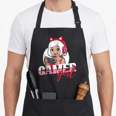 Funny gamer gaming apron - Cartoon girl with red cat headphones holding black phone, GAMER girl text — shown on a black cotton canvas apron against a white background