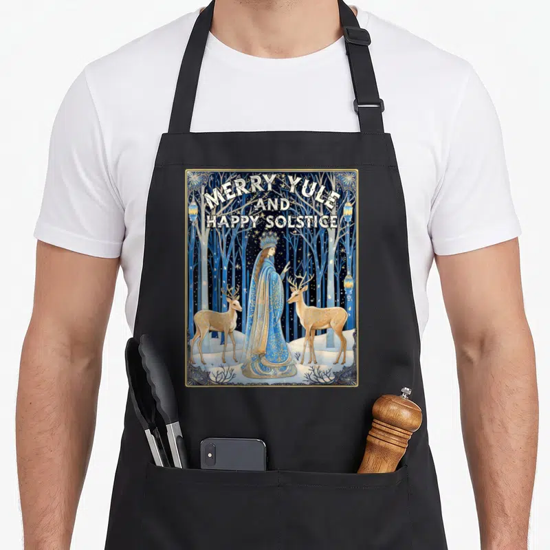 Yule merry christmas apron - Merry Yule and Happy Solstice text above crowned woman and two deer in blue gold art — shown on a black cotton canvas apron against a white background