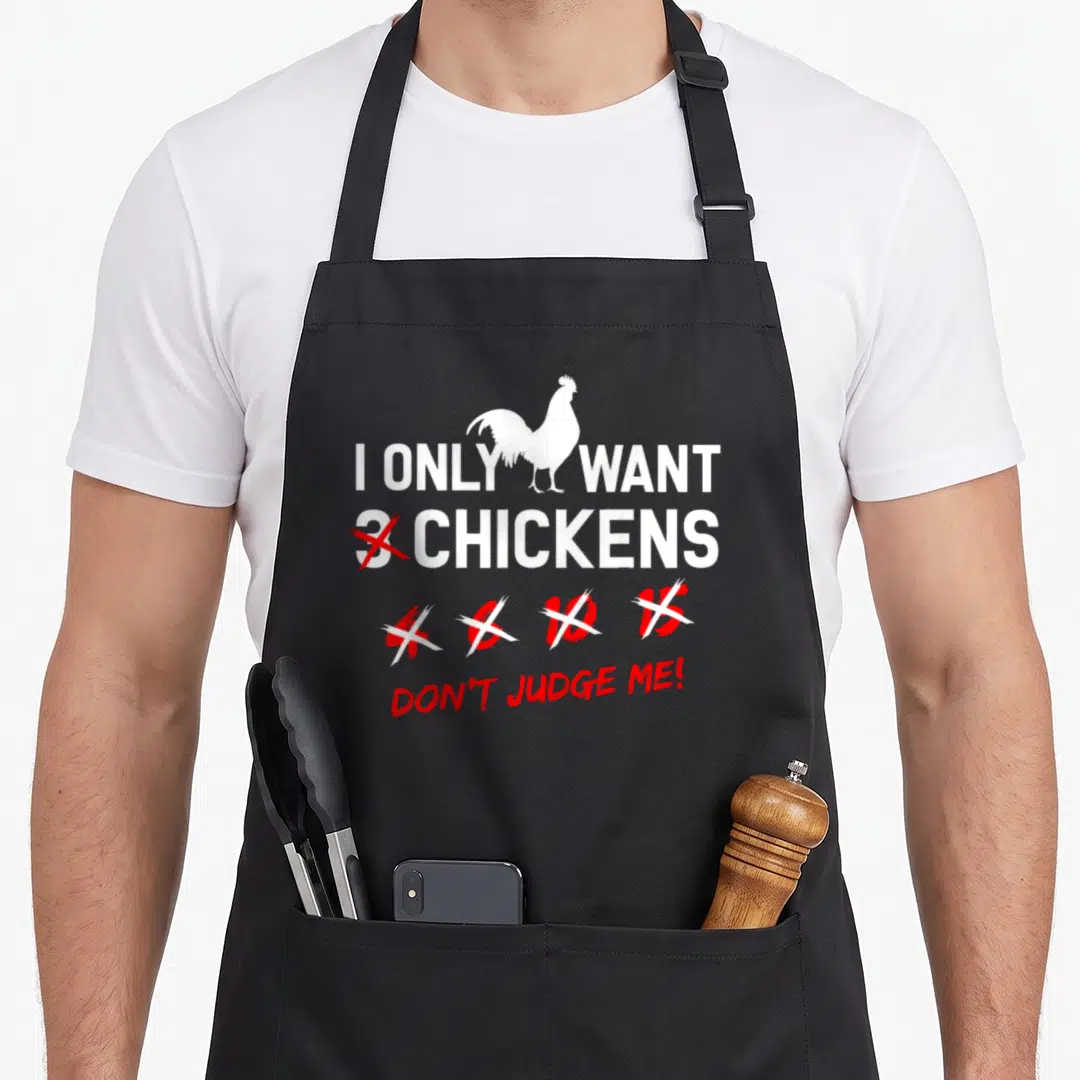 Farm farmer chicken apron - I Only Want 3 Chickens text with white rooster and crossed red numbers — shown on a black cotton canvas apron against a white background