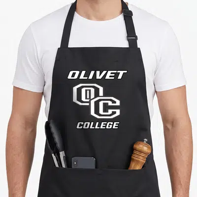 Olivet comet apron - Vertical white OLIVET OC COLLEGE text with black outlines on grey background — shown on a black cotton canvas apron against a white background