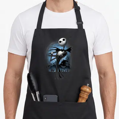 Pose jack apron - Jack Skellington figure in front of blue moon and graveyard silhouette — shown on a black cotton canvas apron against a white background
