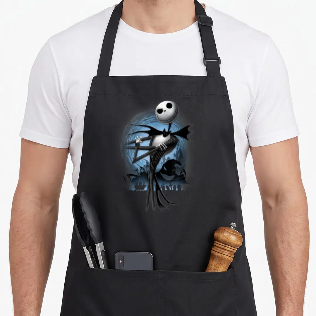 Pose jack apron - Jack Skellington figure in front of blue moon and graveyard silhouette — shown on a black cotton canvas apron against a white background