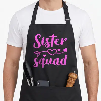 Gang family aprons - Pink Sister squad text with heart arrow graphic — shown on a black cotton canvas apron against a white background