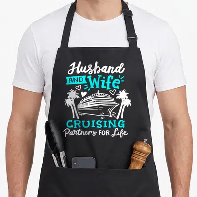 Partner couple apron - White and cyan cruise ship flanked by palm trees with text Husband and Wife Cruising Partners — shown on a black cotton canvas apron against a white background
