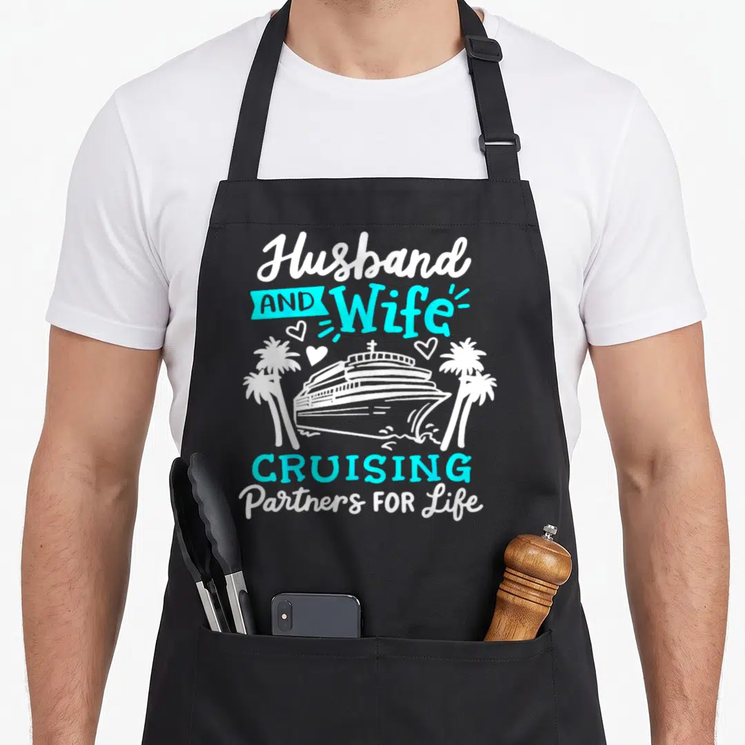 Partner couple apron - White and cyan cruise ship flanked by palm trees with text Husband and Wife Cruising Partners — shown on a black cotton canvas apron against a white background