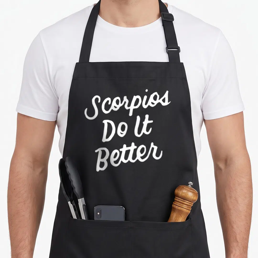 Better zodiac aprons - White stacked script text reading Scorpios Do It Better on black fabric — shown on a black cotton canvas apron against a white background