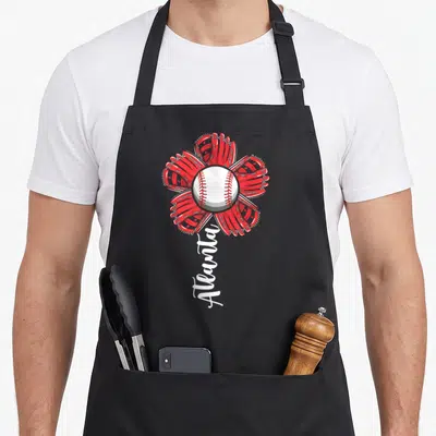 Flower atlanta baseball apron - Red cartoon flower of four baseball gloves around a white ball with vertical Atlanta — shown on a black cotton canvas apron against a white background