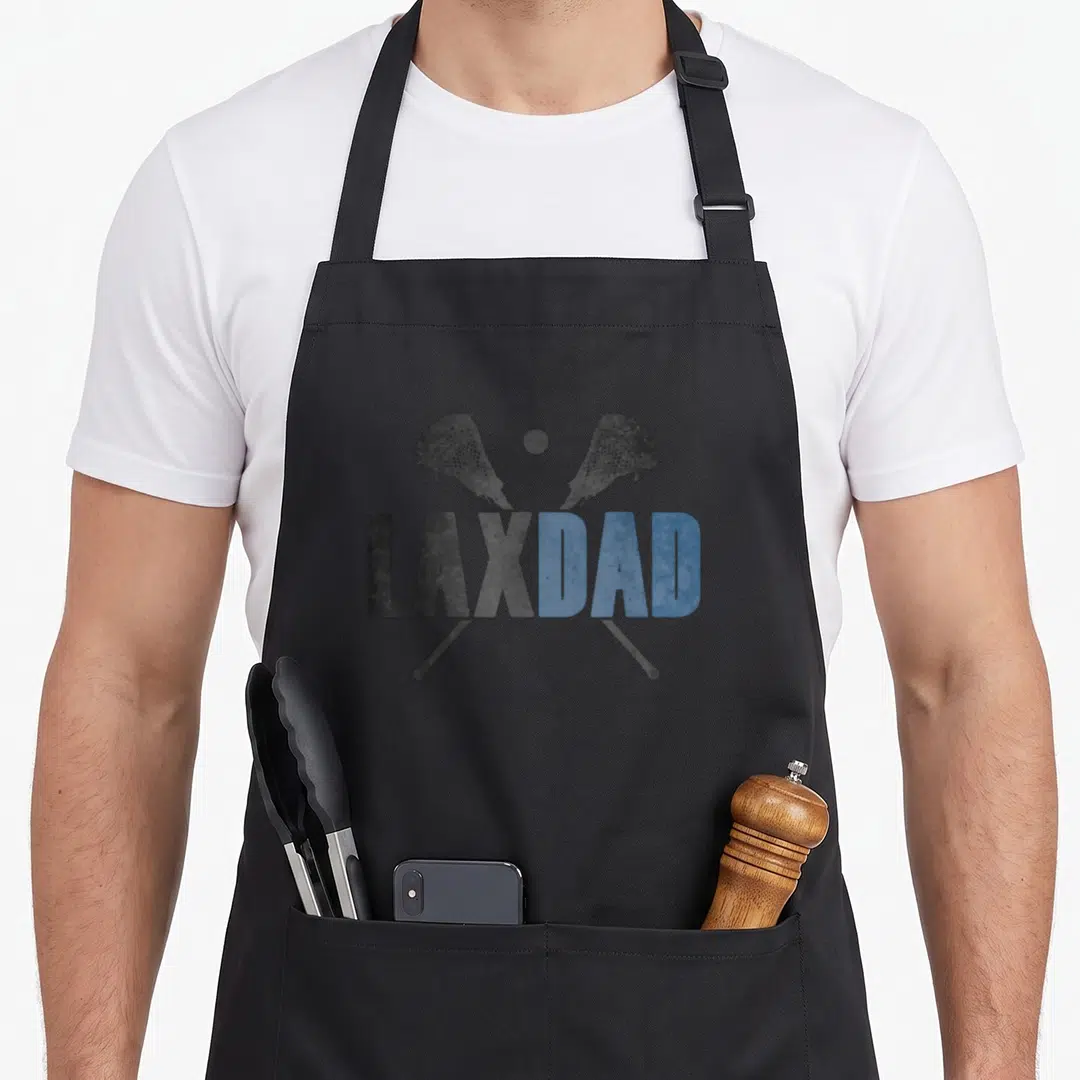 Lax founder apron - Crossed dark grey and blue lacrosse sticks with ball above LAXDAD text in distressed font — shown on a black cotton canvas apron against a white background