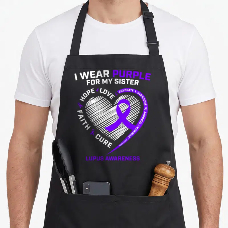 Sister lupus awareness apron - Purple ribbon in white hatched heart with I wear purple for my sister text — shown on a black cotton canvas apron against a white background