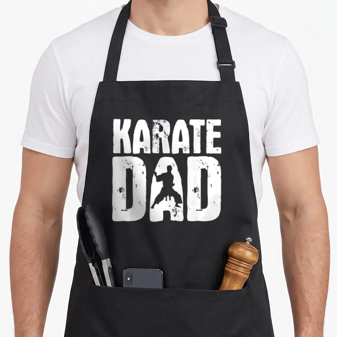 Karate judo apron - Distressed white KARATE DAD text with karate practitioner silhouette inside the letter A on grey — shown on a black cotton canvas apron against a white background