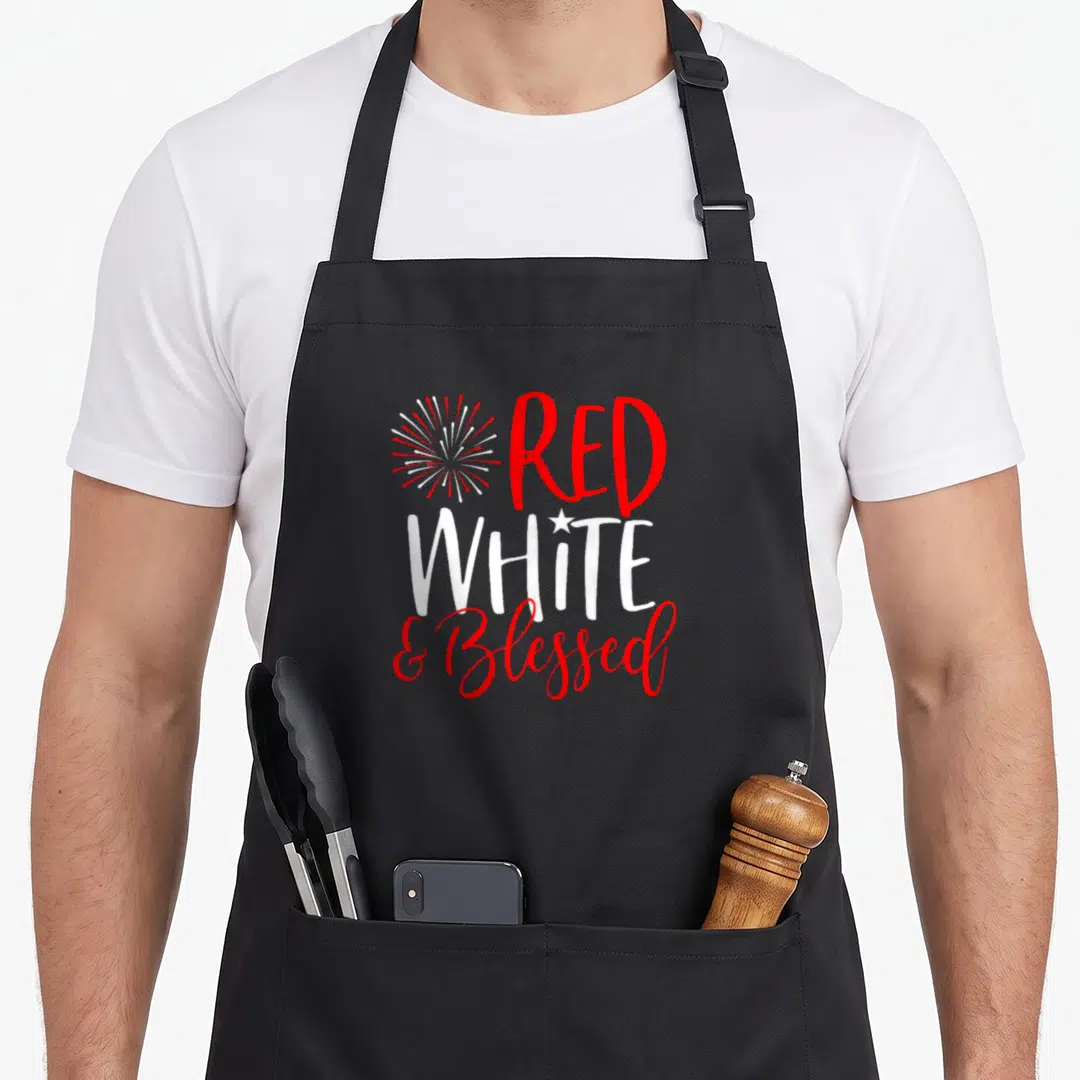 Blessed 4th of july apron - Stacked red and white text reading RED WHITE & Blessed with a firework and star graphic — shown on a black cotton canvas apron against a white background