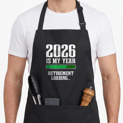 Funny countdown retirement apron - White 2026 IS MY YEAR text above a green loading bar and RETIREMENT LOADING text — shown on a black cotton canvas apron against a white background
