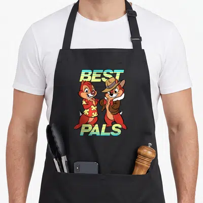 Pal chips apron - Two chipmunks standing side by side with BEST PALS text in striped retro font — shown on a black cotton canvas apron against a white background