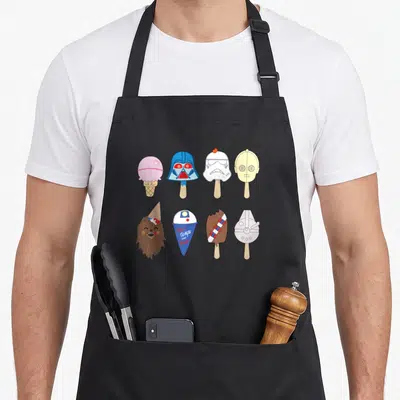 Character ice cream apron - Eight Star Wars characters as popsicles and cones in white blue yellow brown grey cartoon — shown on a black cotton canvas apron against a white background