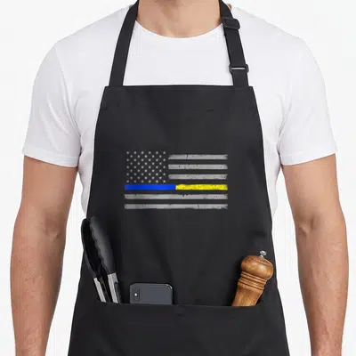 Police line apron - Distressed grey flag with thin blue and yellow horizontal stripes and white stars — shown on a black cotton canvas apron against a white background