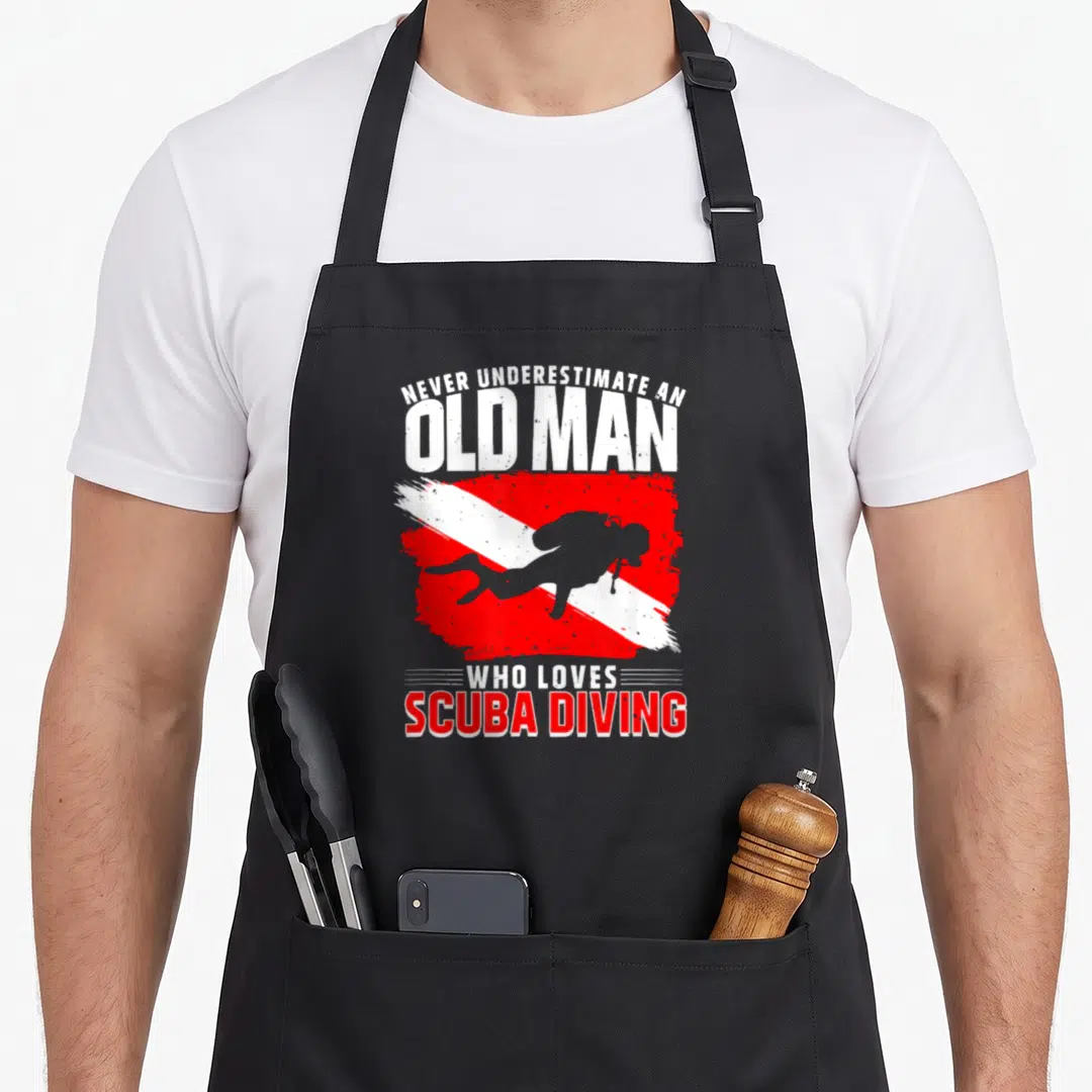 Underestimate diving apron - Diver silhouette on red white diagonal flag with distressed text NEVER UNDERESTIMATE — shown on a black cotton canvas apron against a white background