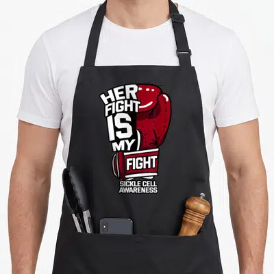 Fight sickle ribbon apron - Red boxing glove with Her Fight Is My Fight and Sickle Cell Awareness text — shown on a black cotton canvas apron against a white background