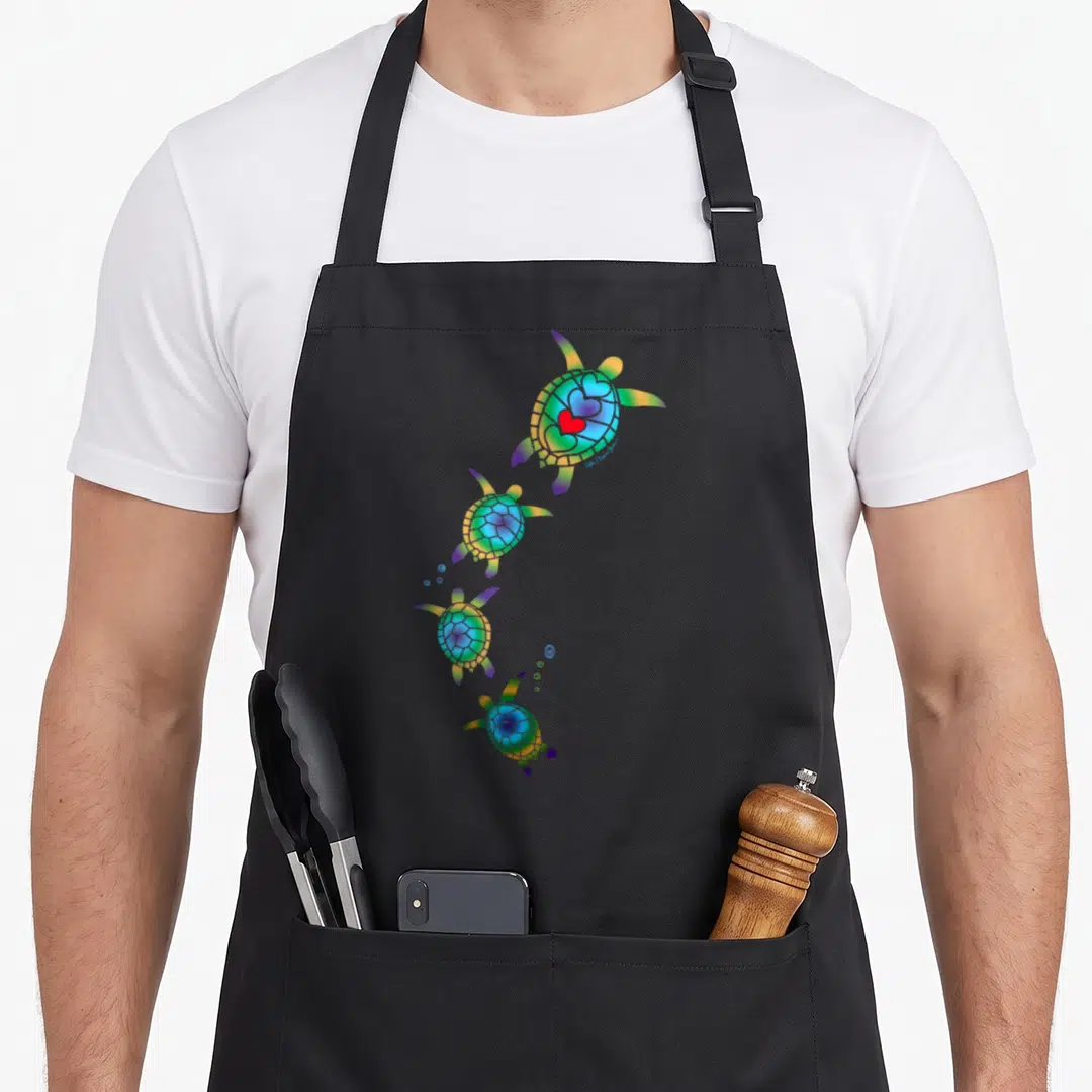 Nautical beautiful apron - Four rainbow sea turtles in a curve with red heart on top shell — shown on a black cotton canvas apron against a white background