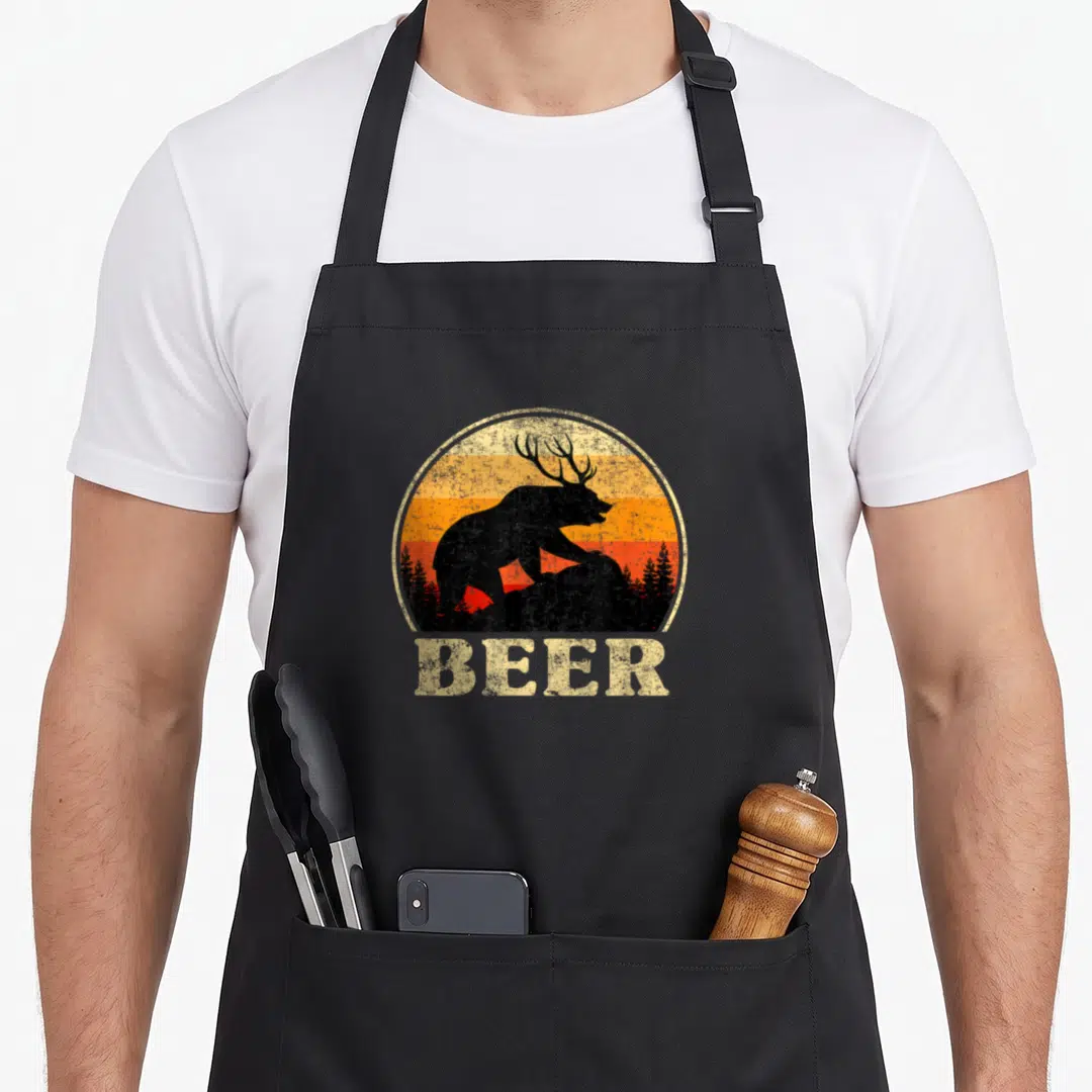 Funny beer st patrick day aprons - Retro bear with antlers silhouette on striped sunset with BEER text below — shown on a black cotton canvas apron against a white background