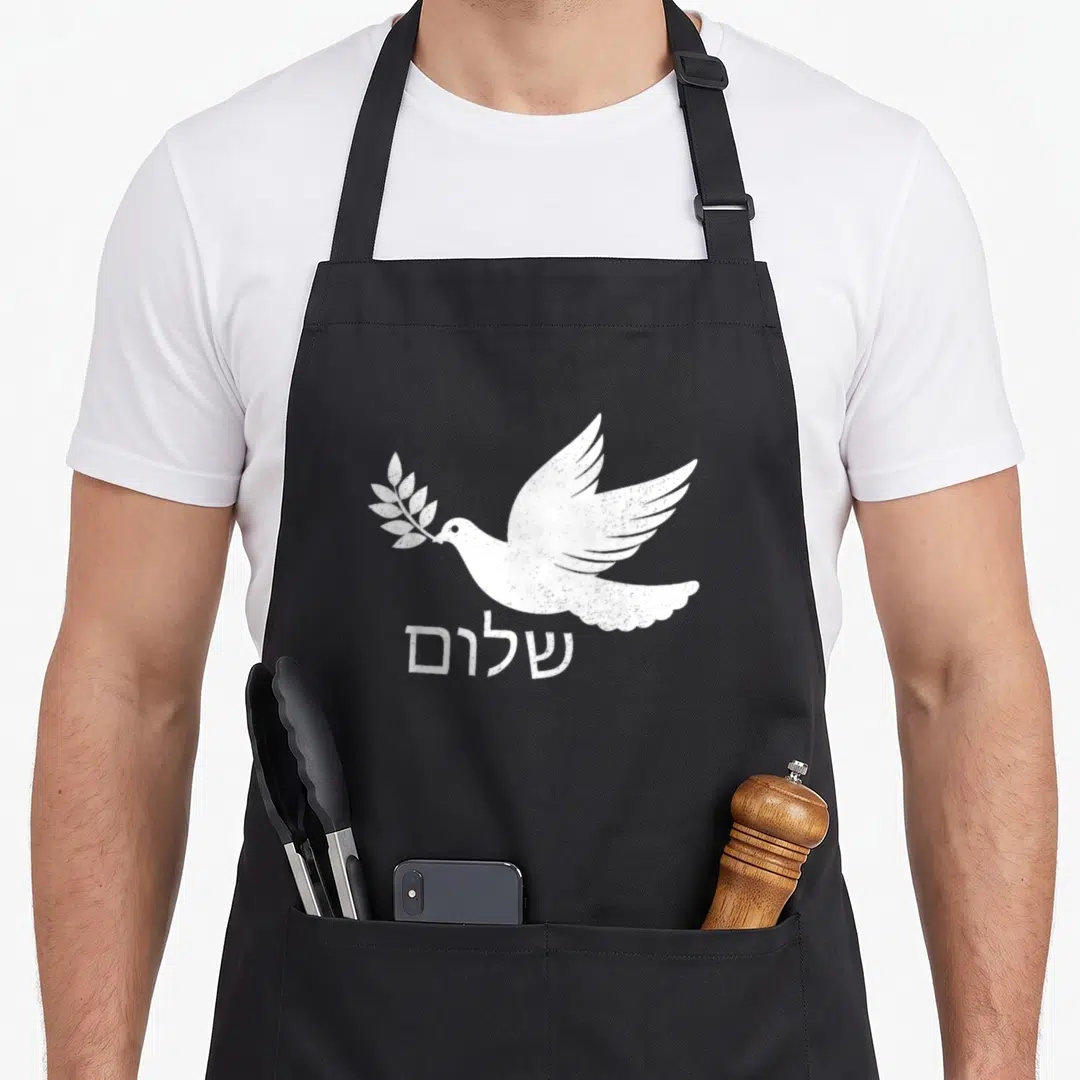 Shalom jewish aprons - White distressed dove holding olive branch above Hebrew text shalom — shown on a black cotton canvas apron against a white background